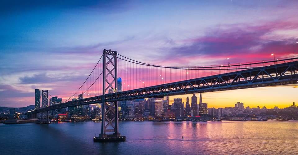 Photo of San Francisco Bay bridge with the skyline at sunset in the background